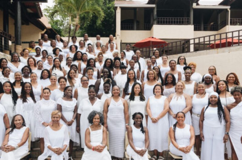 Large group of Black women, all in white, gathered together on stairs