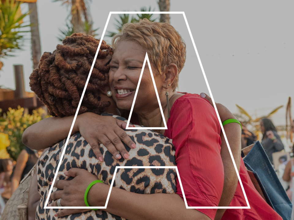 The letter A superimposed over two Black women hugging